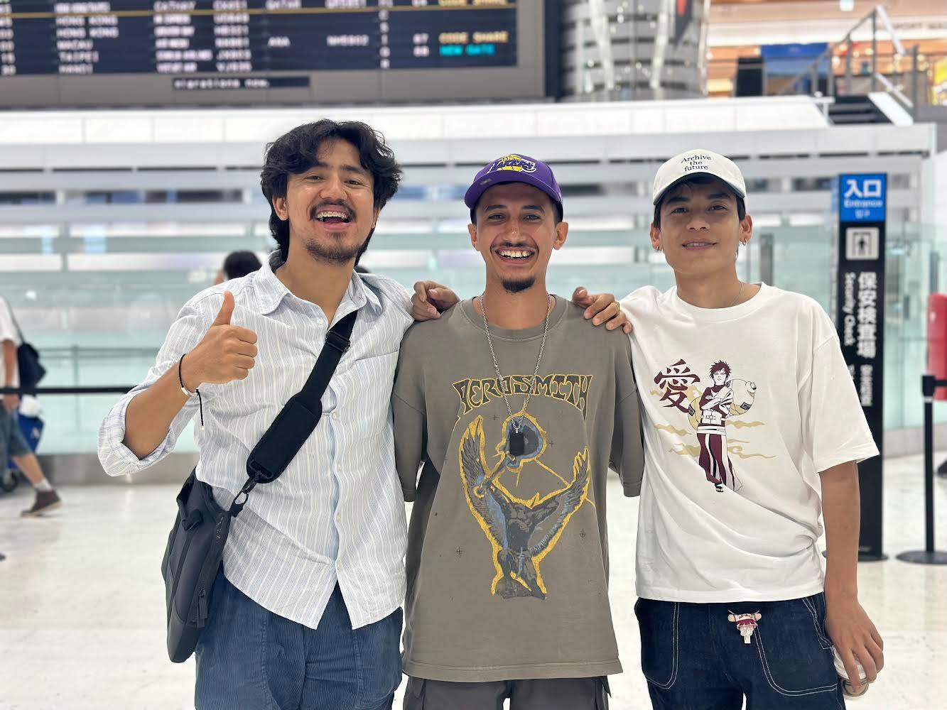 Three travellers with their arms around each other in an airport departure hall