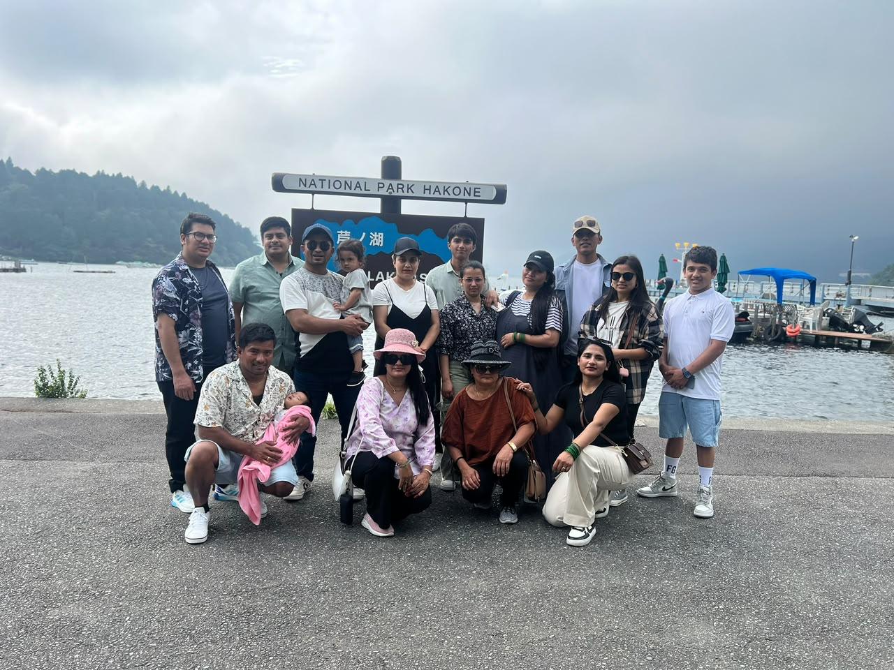 A multi-generational family beside the National Park Hakone sign at Lake Ashi