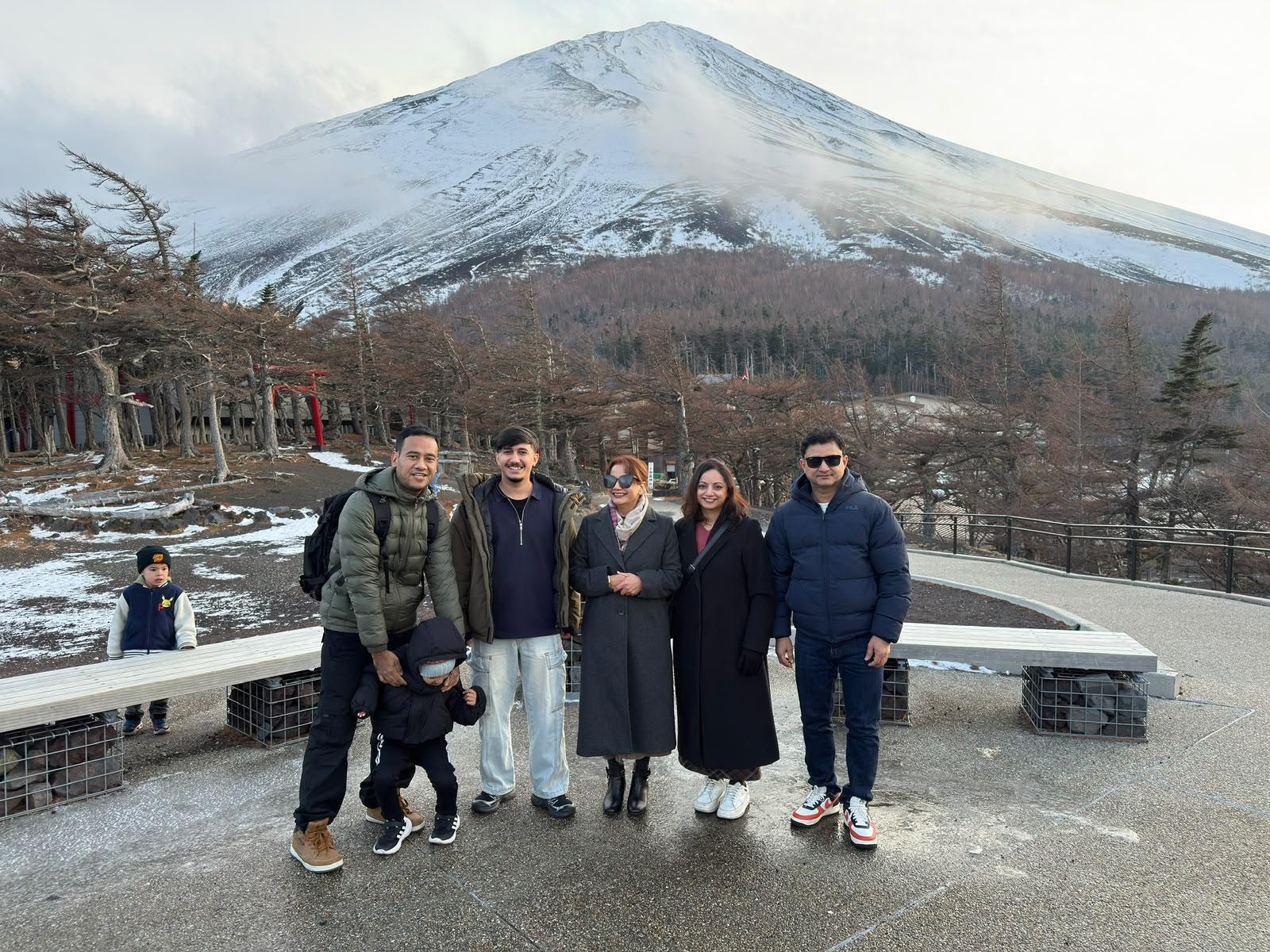 A family in winter coats in front of a snow-covered Mount Fuji