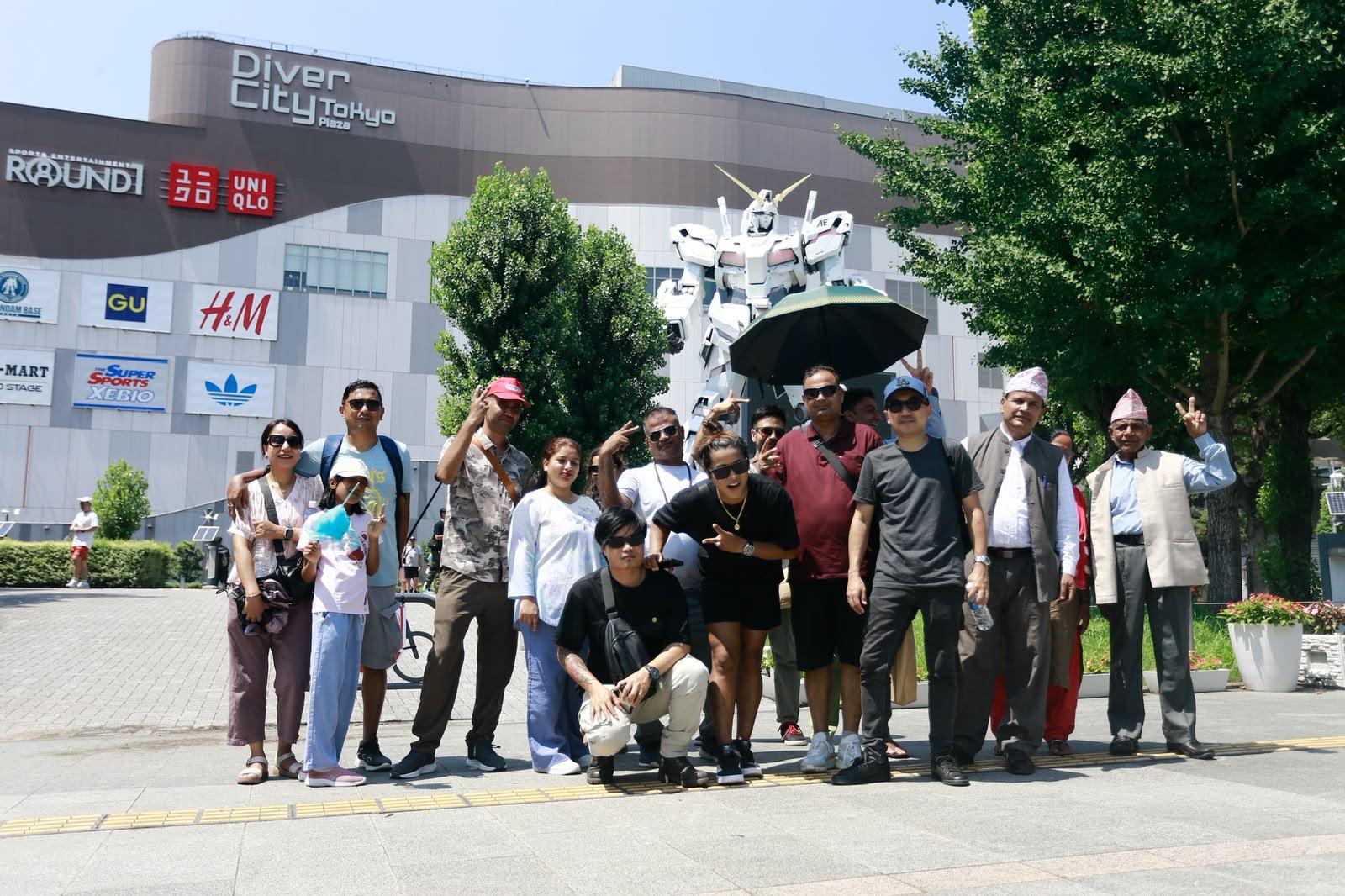 A multi-generational group in front of the Unicorn Gundam statue at DiverCity Tokyo